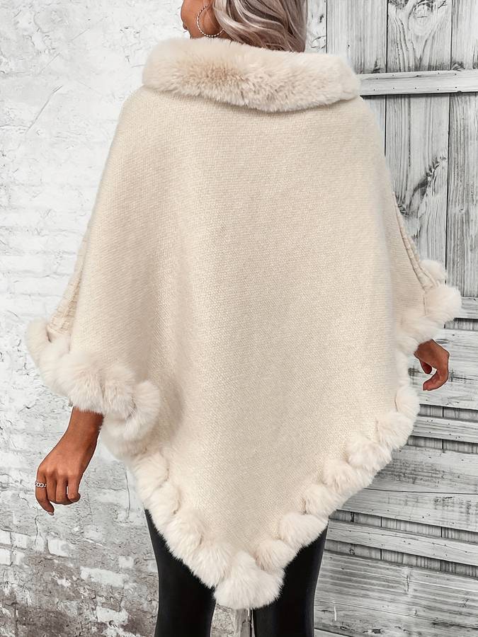 Hazia trendy poncho in crèmekleur, getoond van de achterkant. De poncho heeft een luxueuze, pluizige kraag en rand die langs de onderkant loopt. Ideaal voor een chique en comfortabele uitstraling in de koudere maanden.